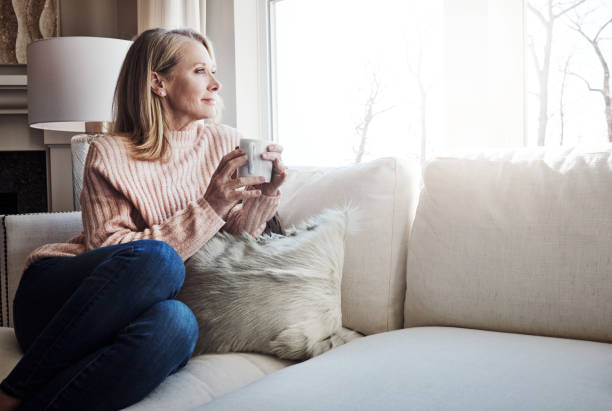 Shot of a mature woman relaxing on the sofa at home with a cup of coffee